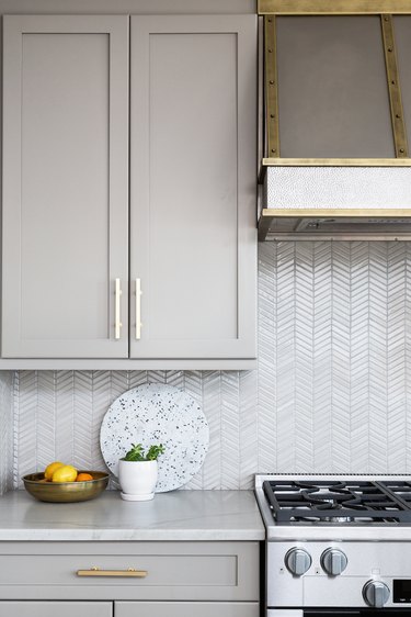 Light gray herringbone kitchen backsplash with light gray cabinetry