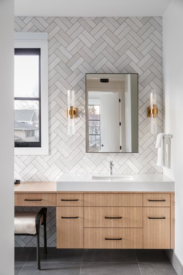 Multicolored gray geometric laid tiles in bathroom with wood cabinetry