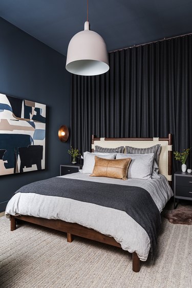 Bold blue walls in bedroom, abstract art on wall