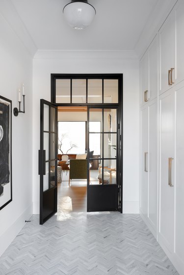 Herringbone gray tile floor in hallways leading to black framed glass doors