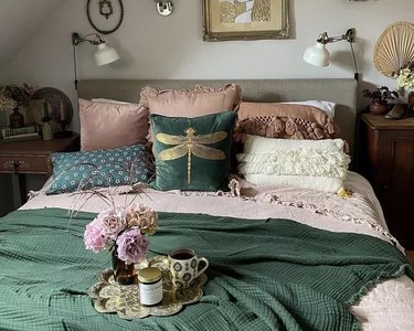 A cottagecore bedroom with green throw and cushions