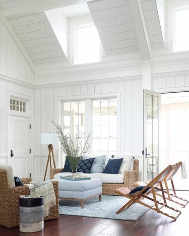 A high ceilinged livingroom with a coastal decor vibe