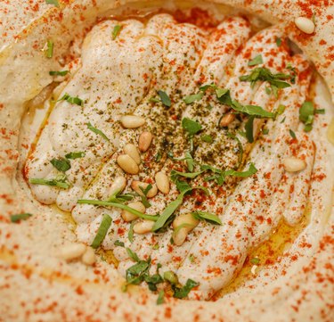 close up image of hummus with pine nuts on top