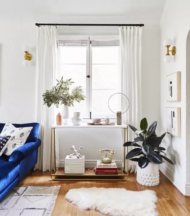 Corner of a white livingroom with brass wall sconces and blue sofa