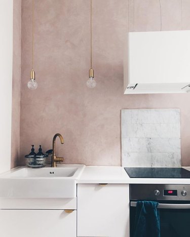 minimal pink kitchen accent wall with marble backsplash and white cabinets