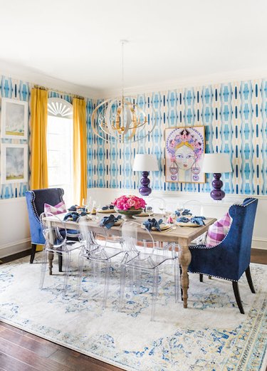 A dining room with blue patterned wallpaper.