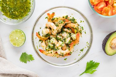 A clear glass bowl featuring the shrimp and chimichurri sauce mixture.