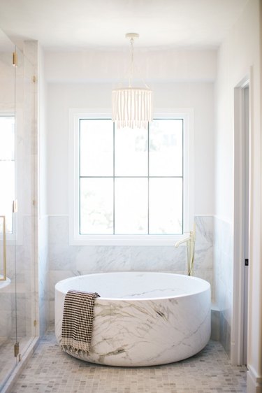 A large, circular marble tub in a marble backdrop.