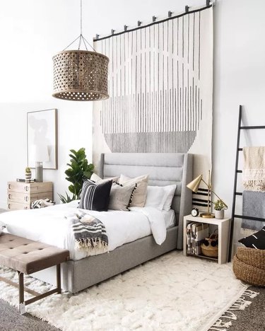 Layered bedroom with rug tapestry and white, grey, and black color scheme