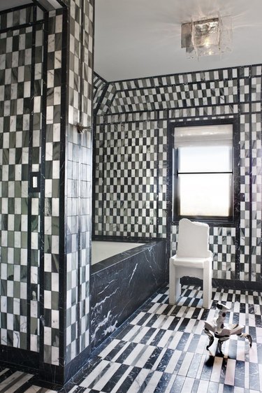 A black marble tub in a checkered bathroom.