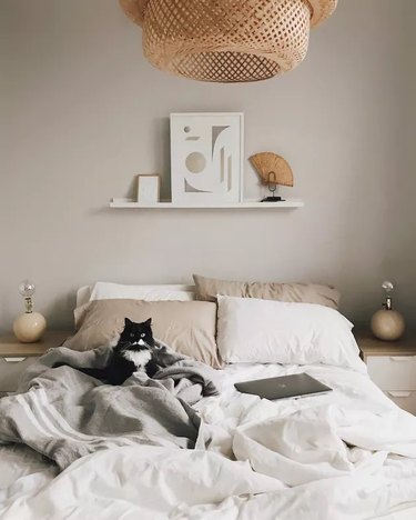 Scandi inspired bedroom with rumpled bedsheets and cat on the bed