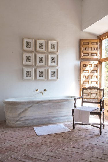 Natural marble tub with crossed tiled flooring.