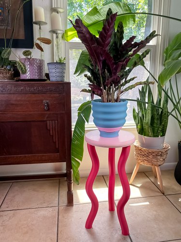 Bright pink table with a blue planter next to a window
