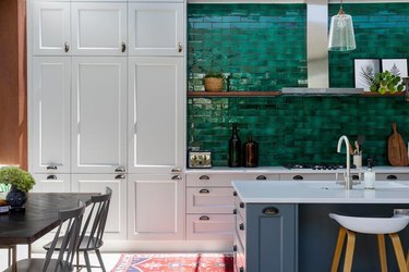 white kitchen cabinets with emerald green backsplash and red runner