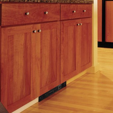 A toe kick heater underneath a wooden kitchen cabinet