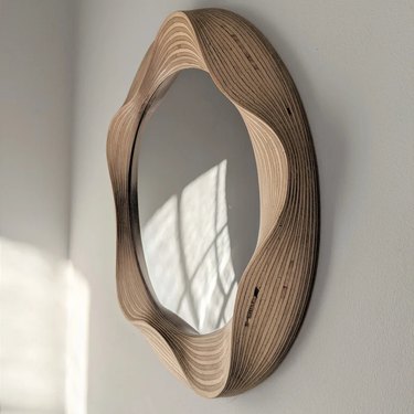 Wooden mirror with a squiggle design on a white wall