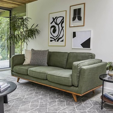 Green midcentury style couch on gray patterned carpet