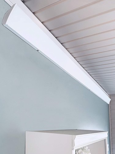 A radiant cove heater on a blue wall with a beadboard ceiling