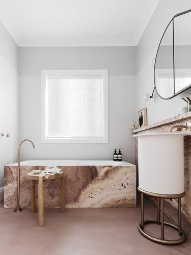 A rose gold marble tub in a dusty pink bathroom