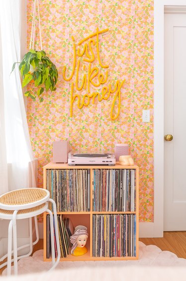 Floral wallpaper with yellow neon sign on top.