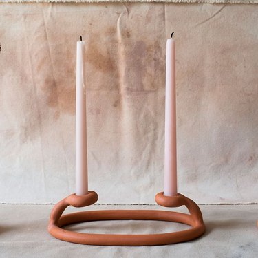two candles in orange ceramic candleholder