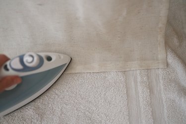 Pressing folded fabric with a hot iron and with a towel underneath the fabric