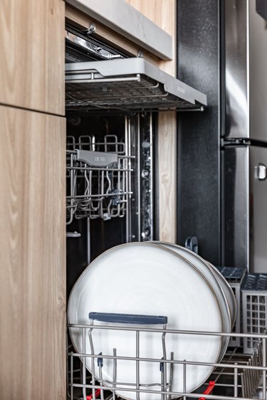 A dishwasher is open, revealing the cutlery tray and bottom rack