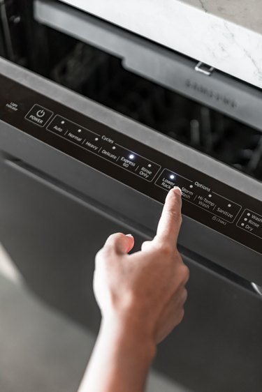 A finger pointing at a lower rack cycle on a dishwasher