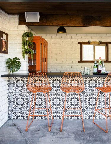 Backyard bar with navy boho tiles and bright orange barstools.