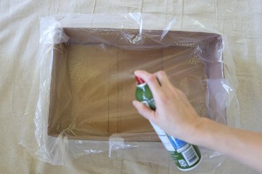 Spraying box lined with plastic with cooking spray