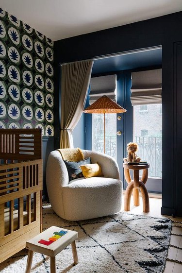 nursery with dark walls and boucle-covered chair