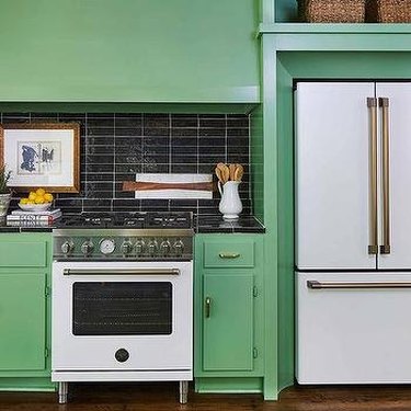green kitchen with white appliances and black tile