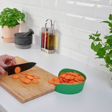 A knife cuts carrots and slide them into a bowl