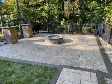 A stamped concrete patio with a dark border, featuring a fire pit in the center