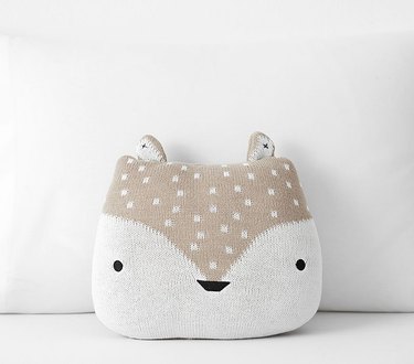 A pillow shaped like a fox with a light brown head.