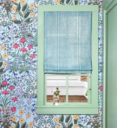 corner of room with blue floral wallpaper, mint green window trim, and aqua window shade