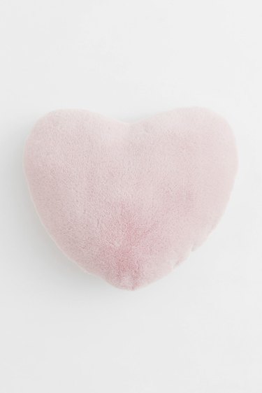 A link pink, fuzzy heart-shaped pillow on a white background.