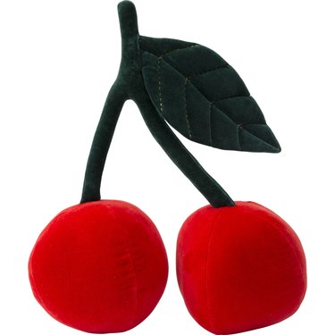 A pillow in the shape of a cherry with two bright red balls connected by a dark green stem with a large leaf at the end.