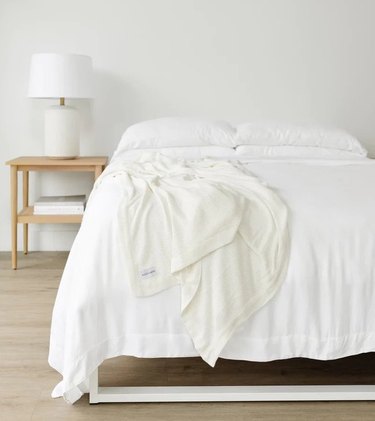 A white bedroom with a bed and nightstand
