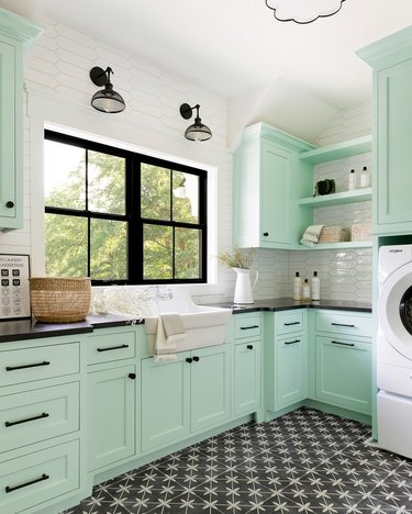 mint green laundry room with black hardware, window trim, and tile floor