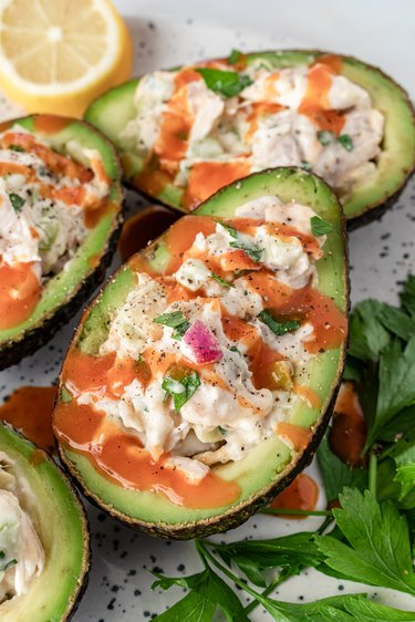 The finished avocados stuffed with chicken salad and drizzled with red-orange hot sauce.