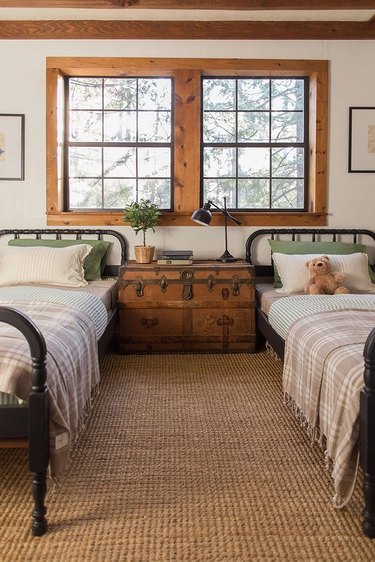 Country-themed kid's room with plaid blankets, jute rugs, and antique chest