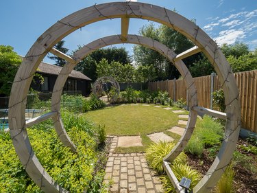 A wooden circular arbor marks the beginning of a garden