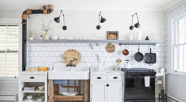 White kitchen with subway tile backsplash, plaster walls and open shelving.