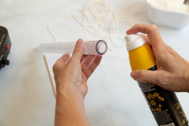 Spraying candle mold with canola oil