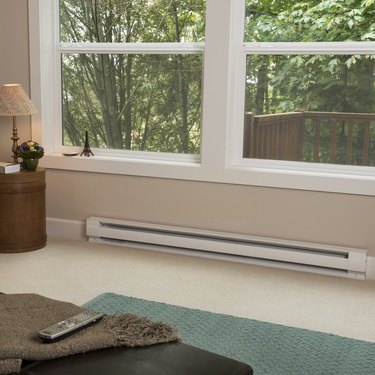 An electric baseboard heater on a carpeted floor