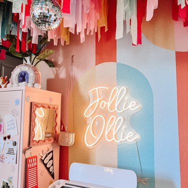 room with striped pastel walls, disco ball, and neon art