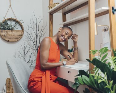 person wearing orange dress leaning against desk