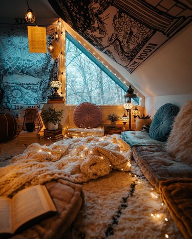 room with angled ceiling, floor cushions, and string lights