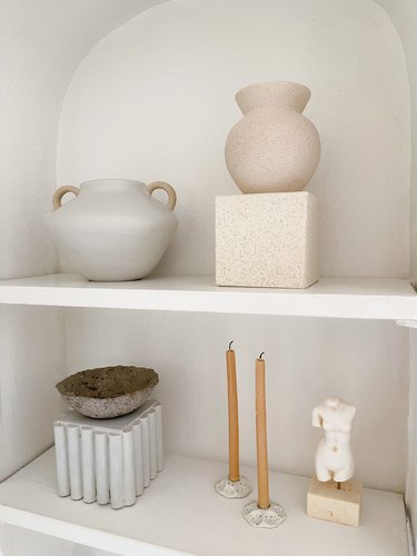 DIY cube risers styled on shelf with vases, candles, and sculptures